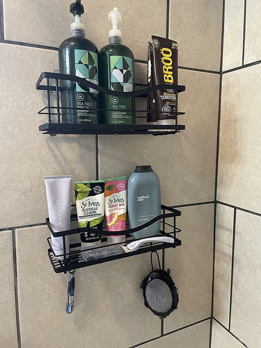 A reviewer's photo showcasing sleek matte black shelves holding bottles inside the shower space.