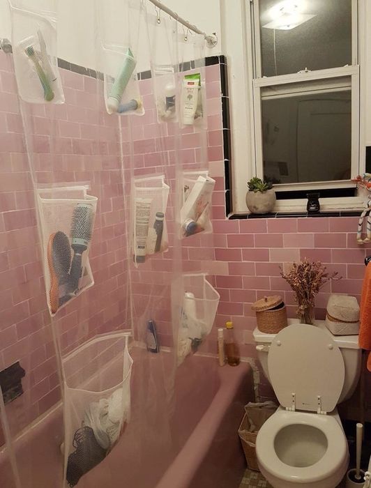 A reviewer's image depicting a shower curtain, filled with shampoos, hairbrushes, and other bathroom essentials neatly stored in its pockets.