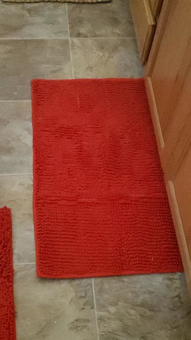 A reviewer’s image of a red bath mat placed in front of a sink.