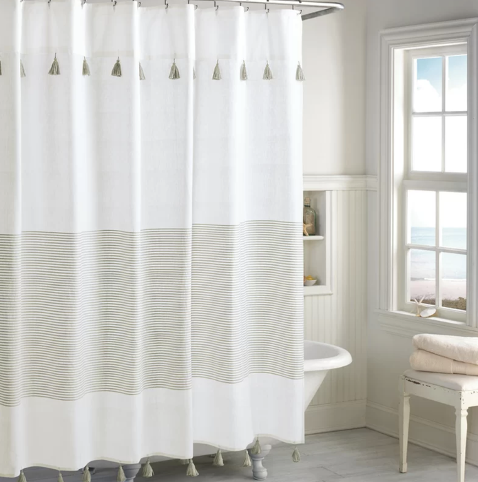A striped cotton shower curtain with black tassels hanging from the edges.