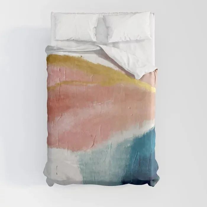 Pink, teal, yellow, blue, and white watercolor duvet cover draped over white sheets against a pristine white background.