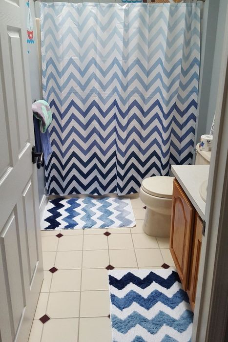 A reviewer’s photo featuring two blue Chevron bath mats in a bathroom, complemented by a matching blue Chevron shower curtain.