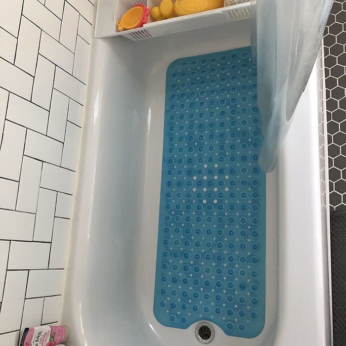 A reviewer’s photo showing the blue bath mat suctioned to the tub.