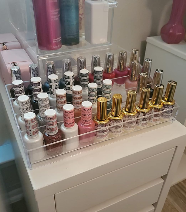 A vanity display showcasing neatly arranged nail polish bottles on a tiered acrylic riser