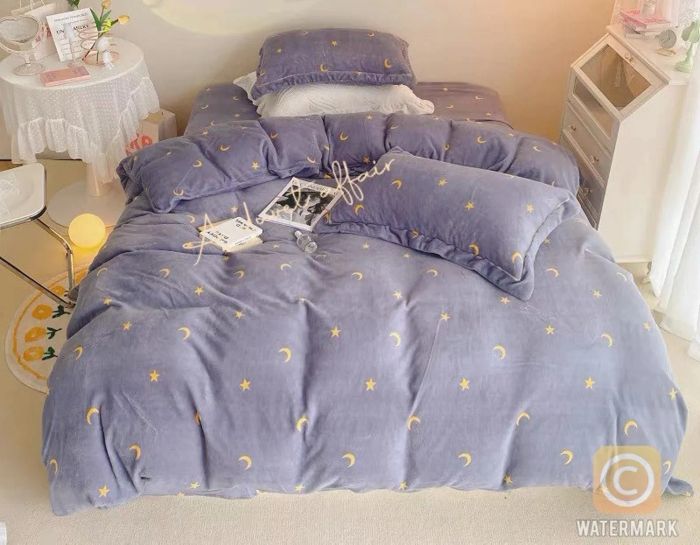 A purple and yellow duvet cover featuring yellow stars and moons, paired with matching pillowcases, placed next to a side table and accent cabinet.