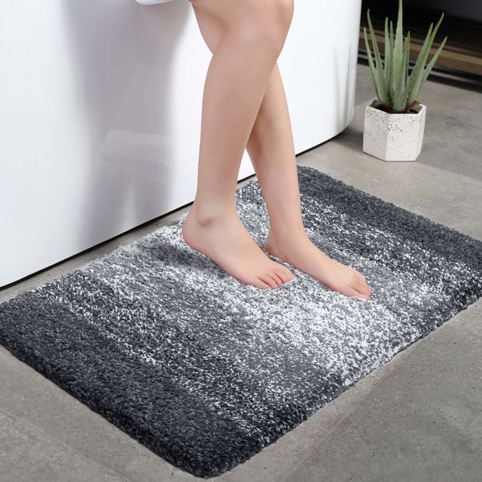 Product image of someone stepping onto a black and white gradient bath mat in front of a shower