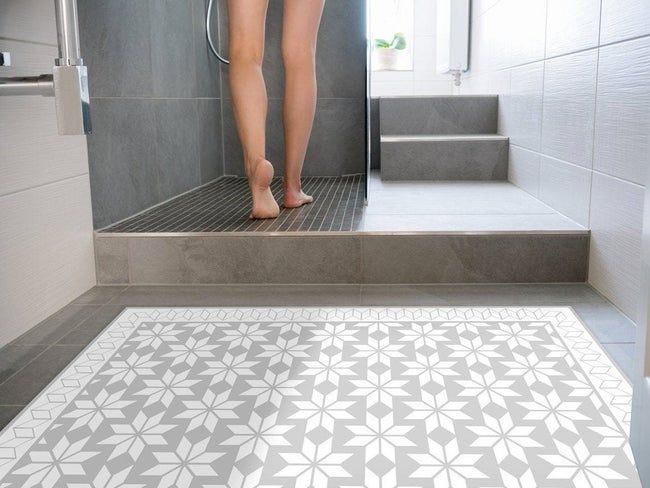A person entering their shower, positioned next to the mat.