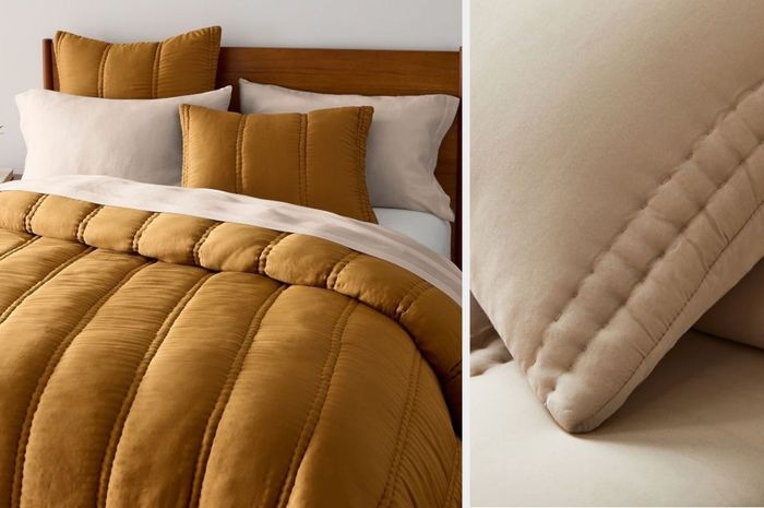 A gold tufted striped comforter with matching shams and beige pillows, placed on a wooden bedframe against a white wall, with a close-up view of the beige material.