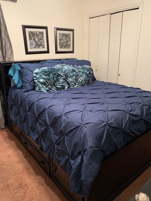 A reviewer image displaying a navy blue comforter set next to white closet doors