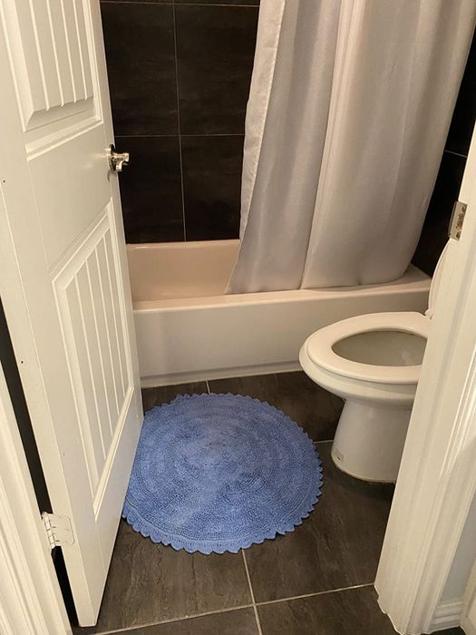 A reviewer’s photo of the round blue bath mat placed in their bathroom.
