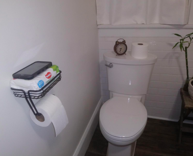 A reviewer photo of the black version of the product, holding a phone and wipes.