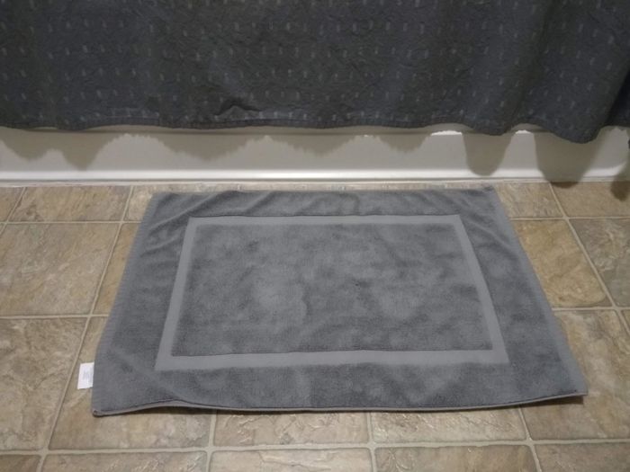 Reviewer photo of a gray bath mat positioned in front of a shower
