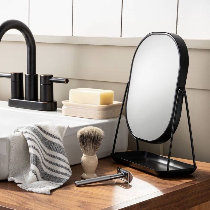 A reviewer photo of the black vanity mirror with a tray base, sitting on a stylishly decorated bathroom counter.