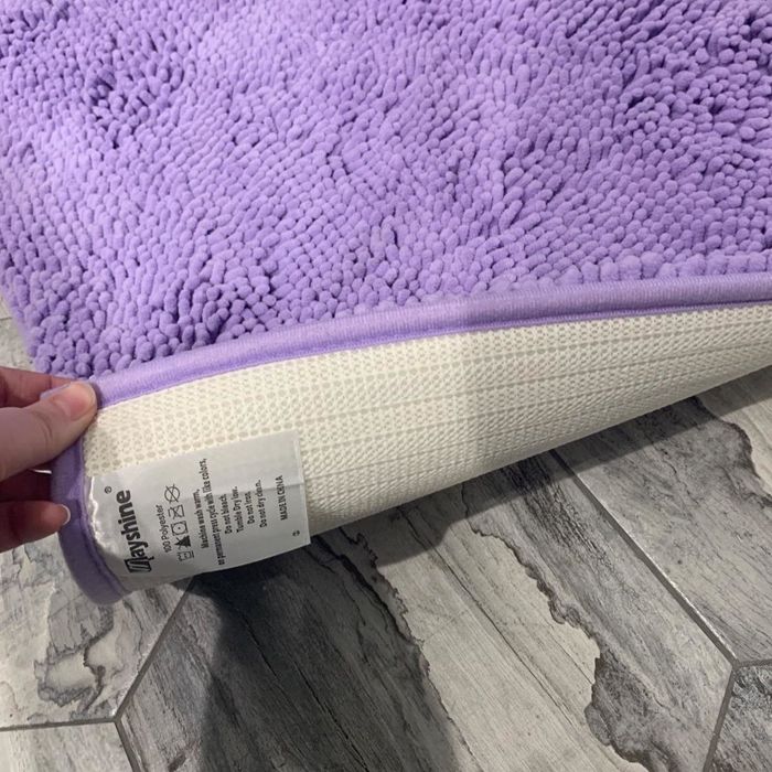 A reviewer’s photo of the purple bath mat being pulled out from its zipped bag.