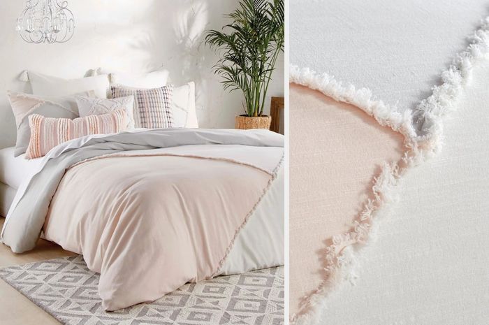 A peach, white, and gray color block comforter with coordinating pillow and throw pillows, placed against a white wall, showing a close-up of the fluffy edging material.