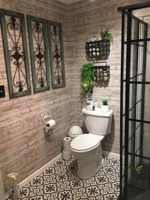 A reviewer applying peel-and-stick wallpaper to the walls in their bathroom