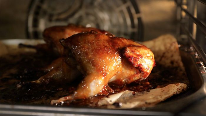 A chicken being roasted inside an oven.