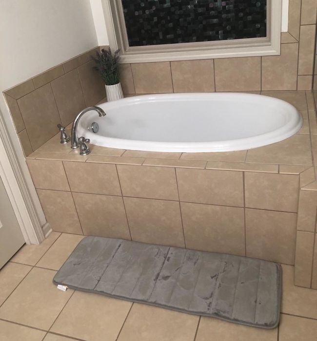 Reviewer photo of the gray bath mat placed in front of a bathtub