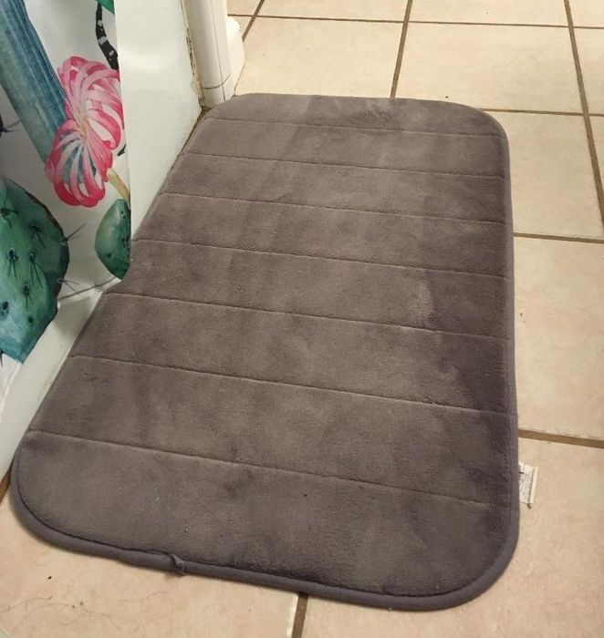 Reviewer photo featuring a gray bath mat placed in front of a shower