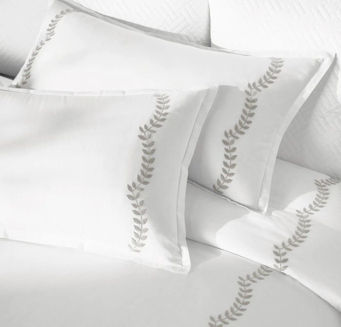 A close-up view of a duvet with dark gray vines embroidered in a scalloped pattern.