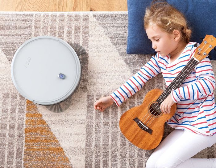 The robot vacuum positioned next to a sleeping child