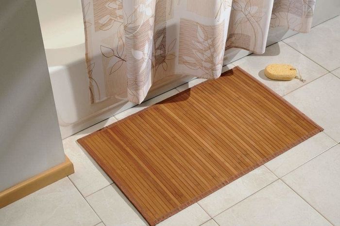 A lifestyle photo showing the bamboo mat placed in front of a shower.