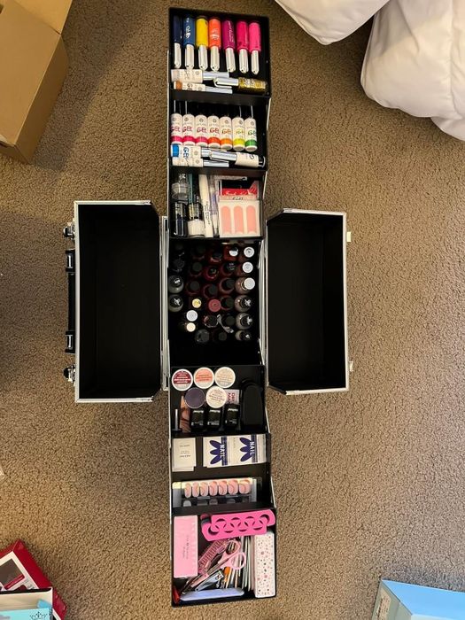A makeup organizer with open tiered trays, showcasing a variety of cosmetics.