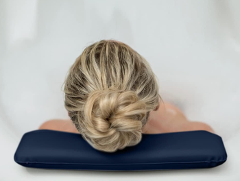 A person is lying back with their head resting on a cushioned bath pillow, fully enjoying their soak.
