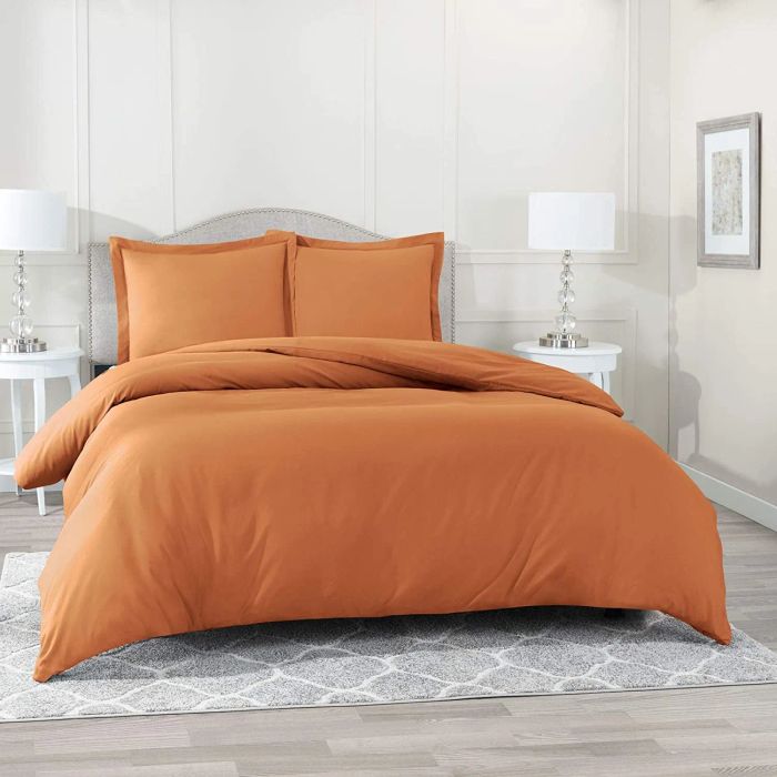 Orange duvet cover with matching pillowcases resting on a gray bed frame, accompanied by two matching wooden nightstands.