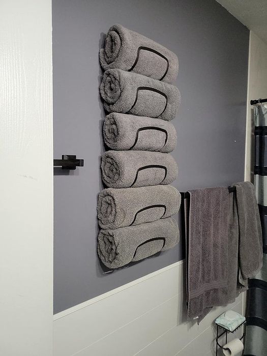 A reviewer’s towel rack holding six neatly rolled grey towels.