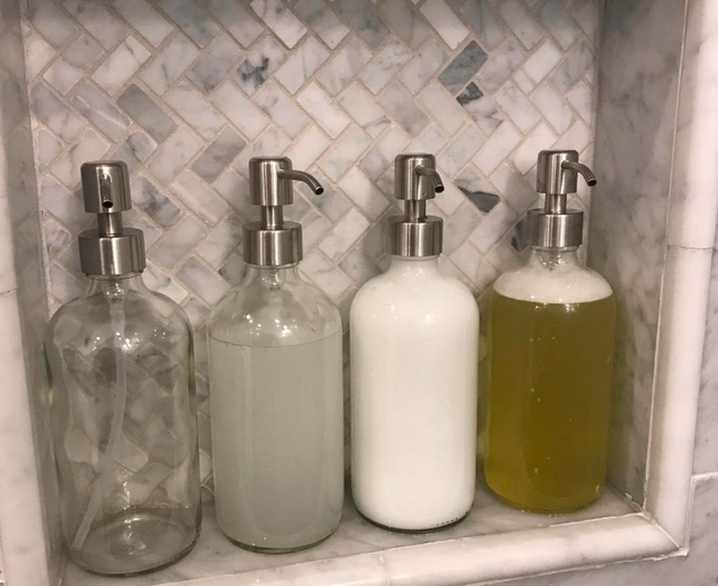 A customer review photo showing four stylish soap dispensers in their shower.
