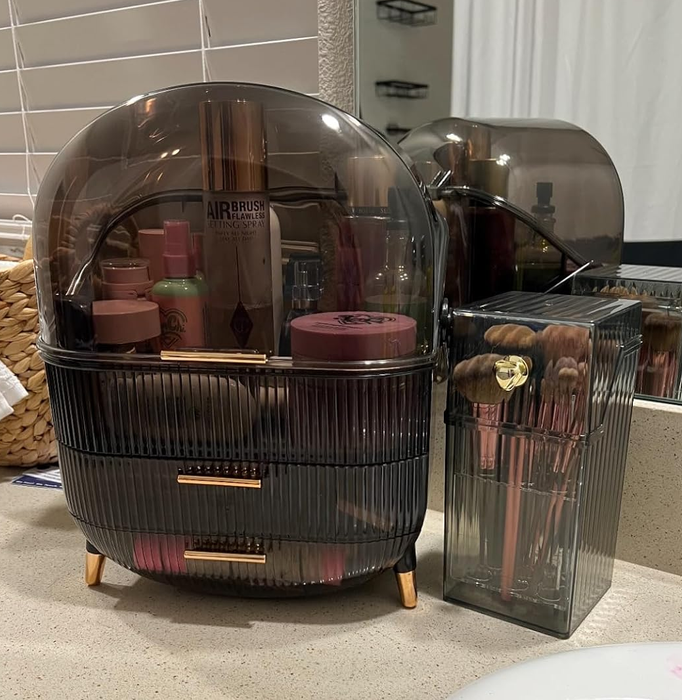 A bathroom countertop featuring a modern makeup organizer filled with cosmetics, brushes neatly arranged in a holder, and a visible sink in the background.