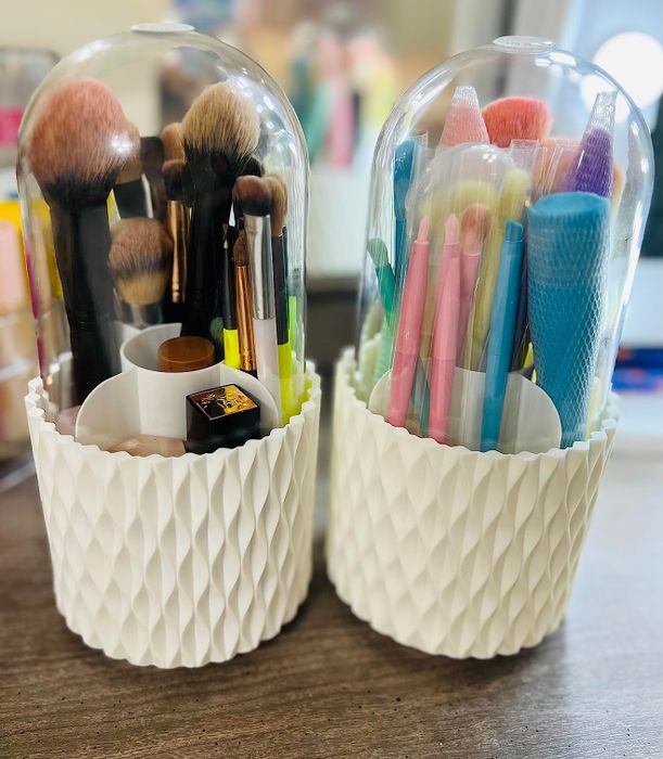 Organize makeup brushes and tools in stylish textured holders with transparent dome covers, ideal for a clean and functional tabletop display.