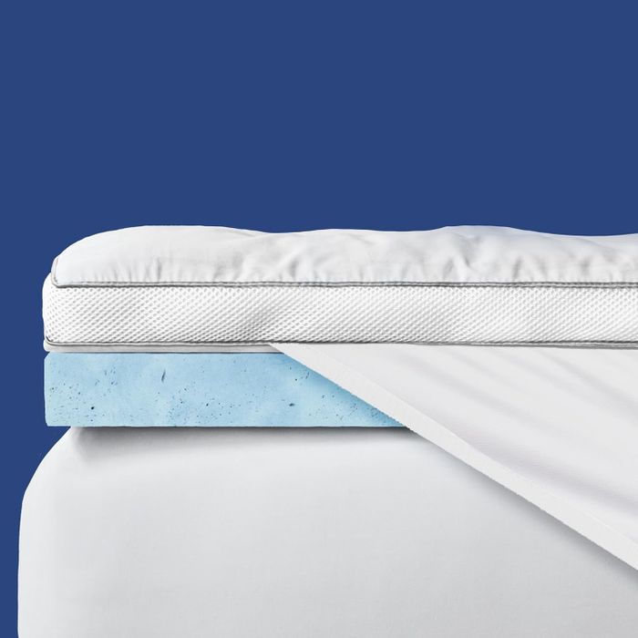 A blue mattress topper placed beneath the mattress pad