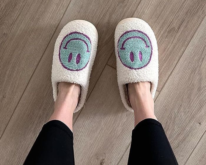 A reviewer sporting blue and purple slippers featuring smiley faces