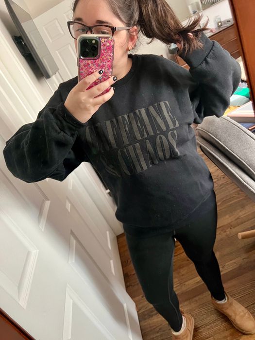 Mytour editor rocking a black sweatshirt with the words 'caffeine and chaos' printed on it