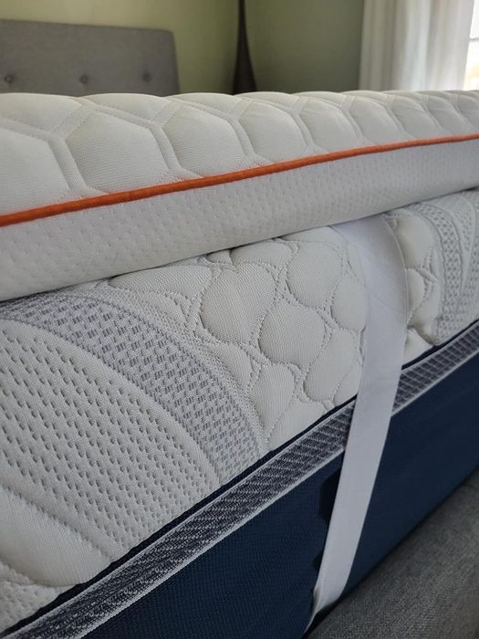 Close-up of a neatly arranged mattress and topper, with a textured surface, held together by a strap