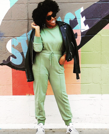 A reviewer wearing a matching green sweatshirt and pants set