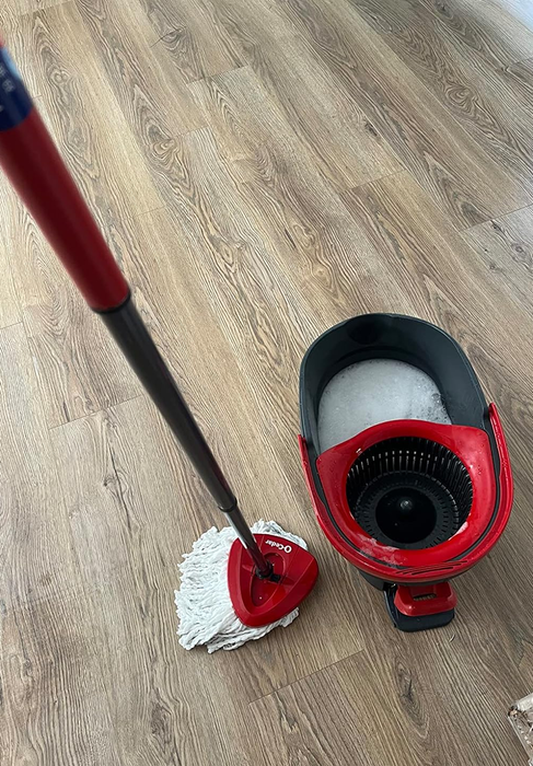 A mop standing next to its bucket