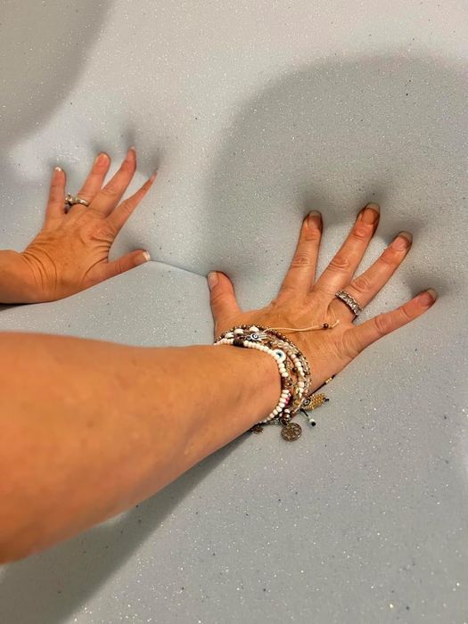 A reviewer pressing their hands into the mattress topper