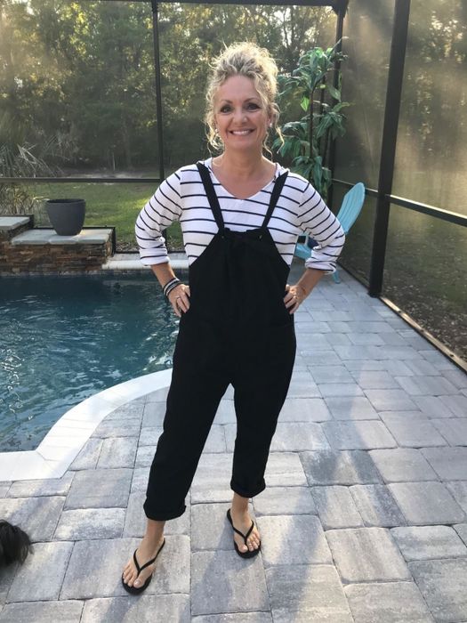 A reviewer pictured wearing the black Aedvoouer Women's Jumpsuit by the pool in their backyard