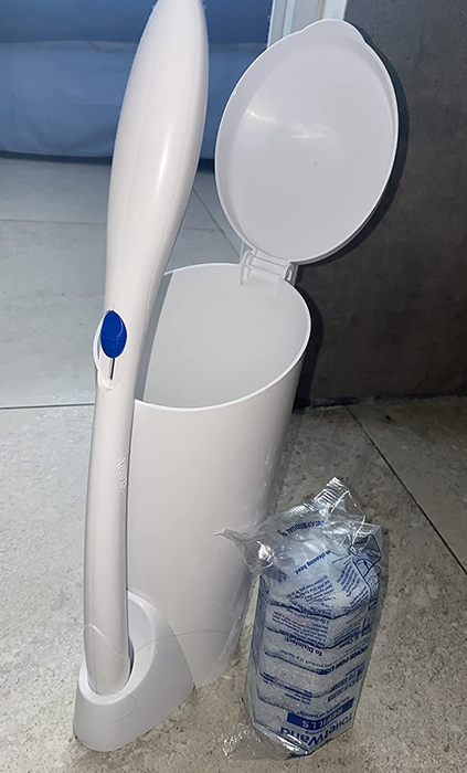 A reviewer’s photo featuring the white toilet wand and holder placed next to a pack of disposable sponge heads.