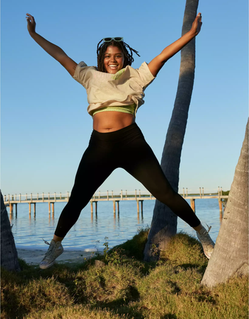 A model leaping in the air while sporting black leggings
