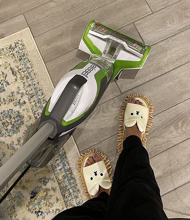 A reviewer wearing the mop slippers while cleaning the floor.
