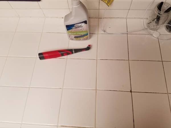A photo showing half of the reviewer’s tile floor with dirty grout, while the other half is spotless and clean.