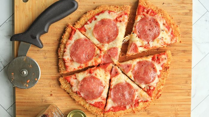 A pizza cut into slices on a wooden board.