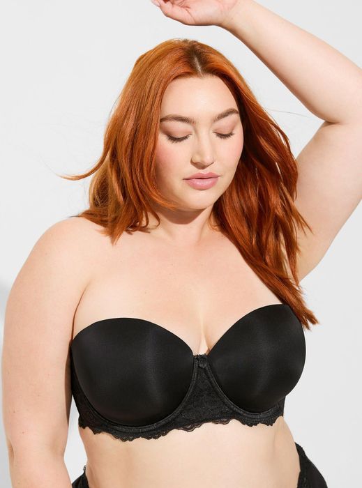 A model striking a pose in a black strapless bra with delicate lace accents.