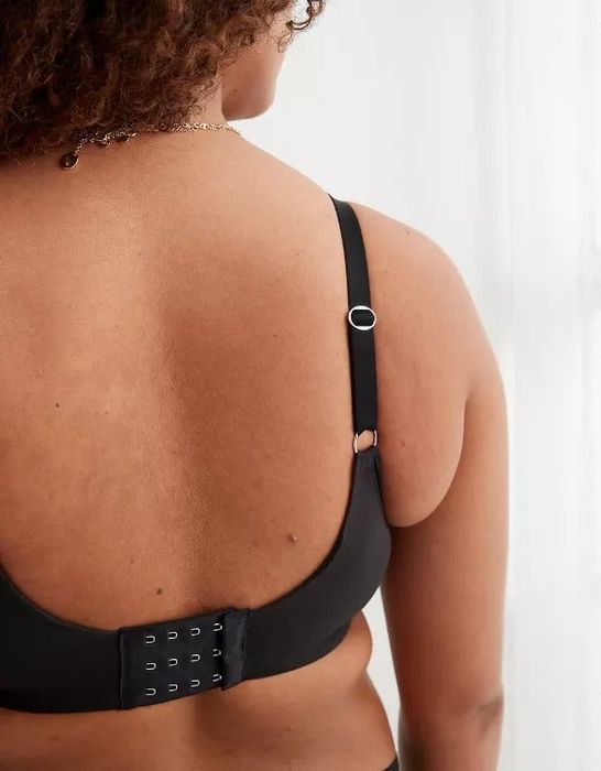 A close-up shot of a model wearing a black bra, emphasizing the back closure and adjustable straps for added comfort.