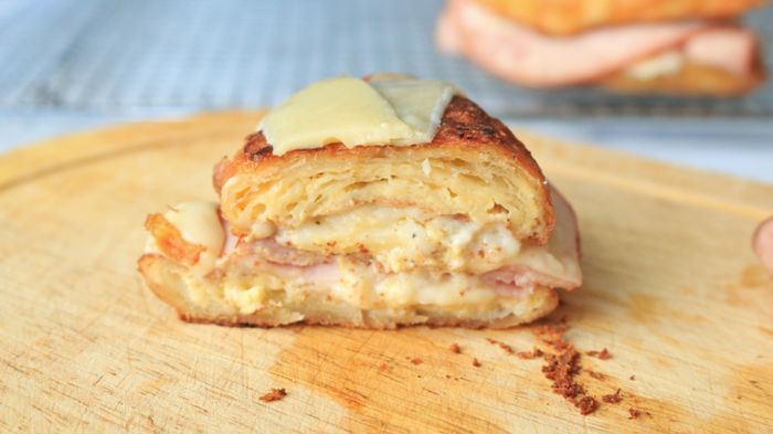 Croissant sandwich sliced in half to reveal the gooey layers inside.