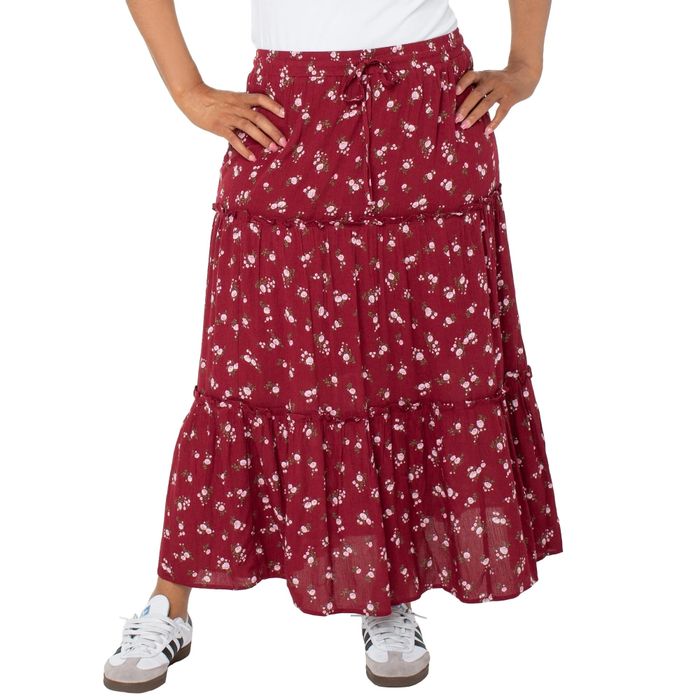 A person rocking a floral maxi skirt paired with a white top and sneakers, confidently posing with hands on hips in a shopping feature article.